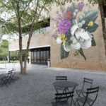 A large-scale mural of white, yellow, and pink flowers painted on a brick building.