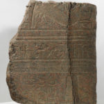 A piece of granite with a human figure and hieroglyphic symbols carved into its surface. Alternate view.