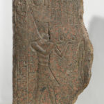 A piece of granite with a human figure and hieroglyphic symbols carved into its surface. Alternate view.