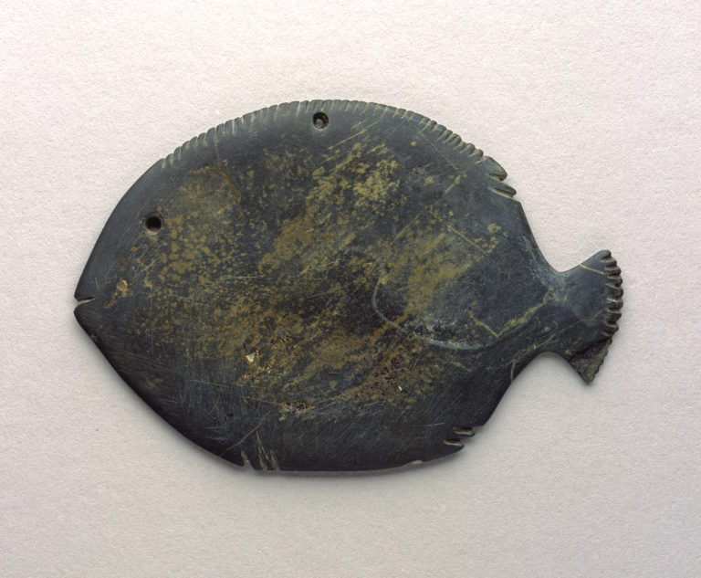 A dark gray, fish-shaped object with carved fins at the top and bottom.