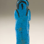 A small blue sculpture of a male figure wearing a long garment. The details of his face, wig, and hands are painted in black. There are hieroglyphs on the figure’s lower front body. View of reverse.