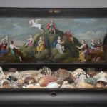 Detail view of ebony cabinet with top door open, showing an oil painting of a scene from Greek mythology and a collection of seashells.
