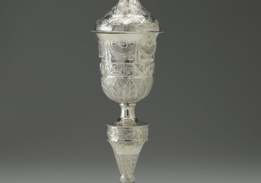A silver goblet featuring intricate floral patterns and a flower blossom design at the top.