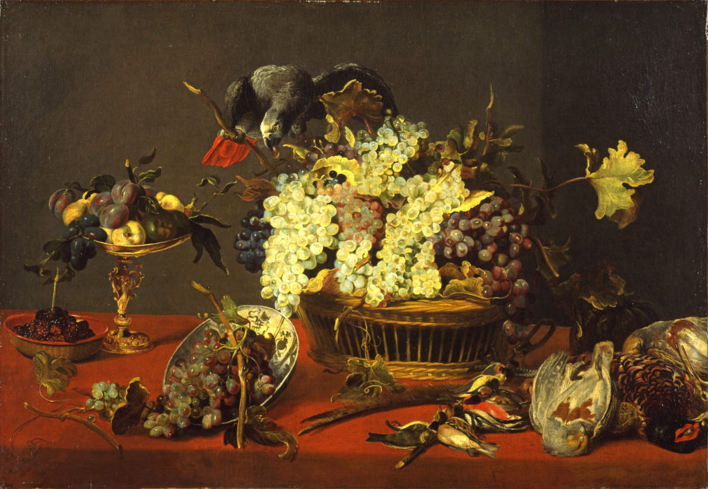 An oil painting of an African gray parrot standing on a basket of grapes, eating. Below are other lavishly displayed fruits and recently hunted fowl on a deep red tablecloth.