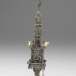 A silver filigree tower featuring two gold flags on the center section and a gold deer figure at the top.