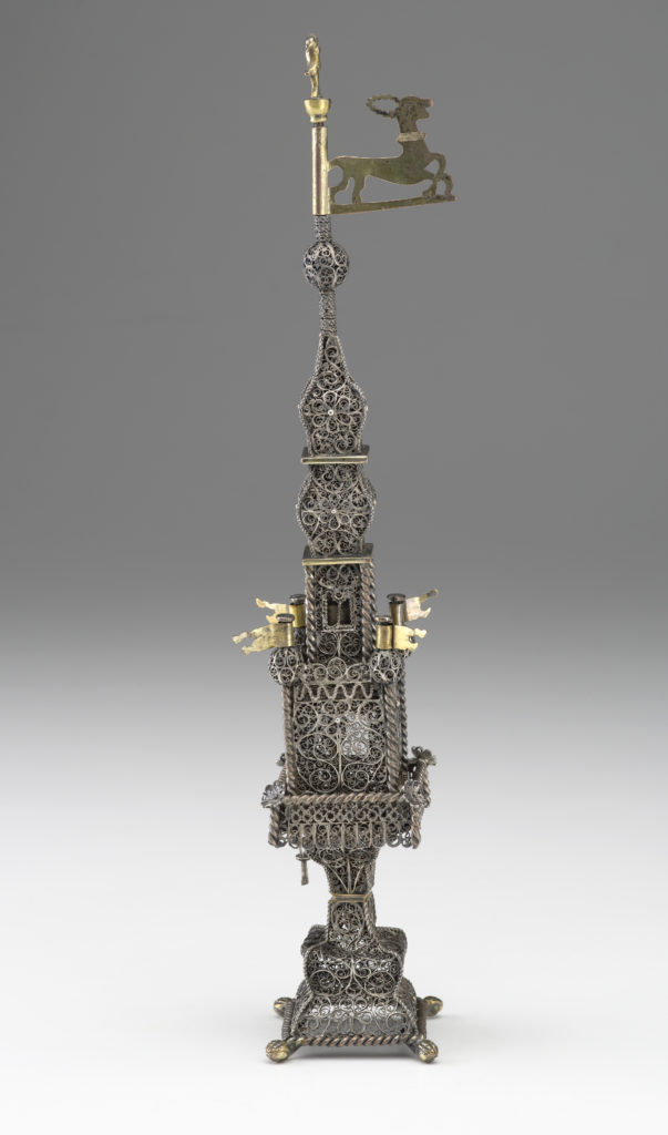 A silver filigree tower featuring two gold flags on the center section and a gold deer figure at the top.
