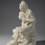 A white marble sculpture of a father and daughter sitting. The daughter sits slightly lower than the father while she works on a weaving project. Her father is carving an arrowhead. A slaughtered deer lies at their feet. Side view.