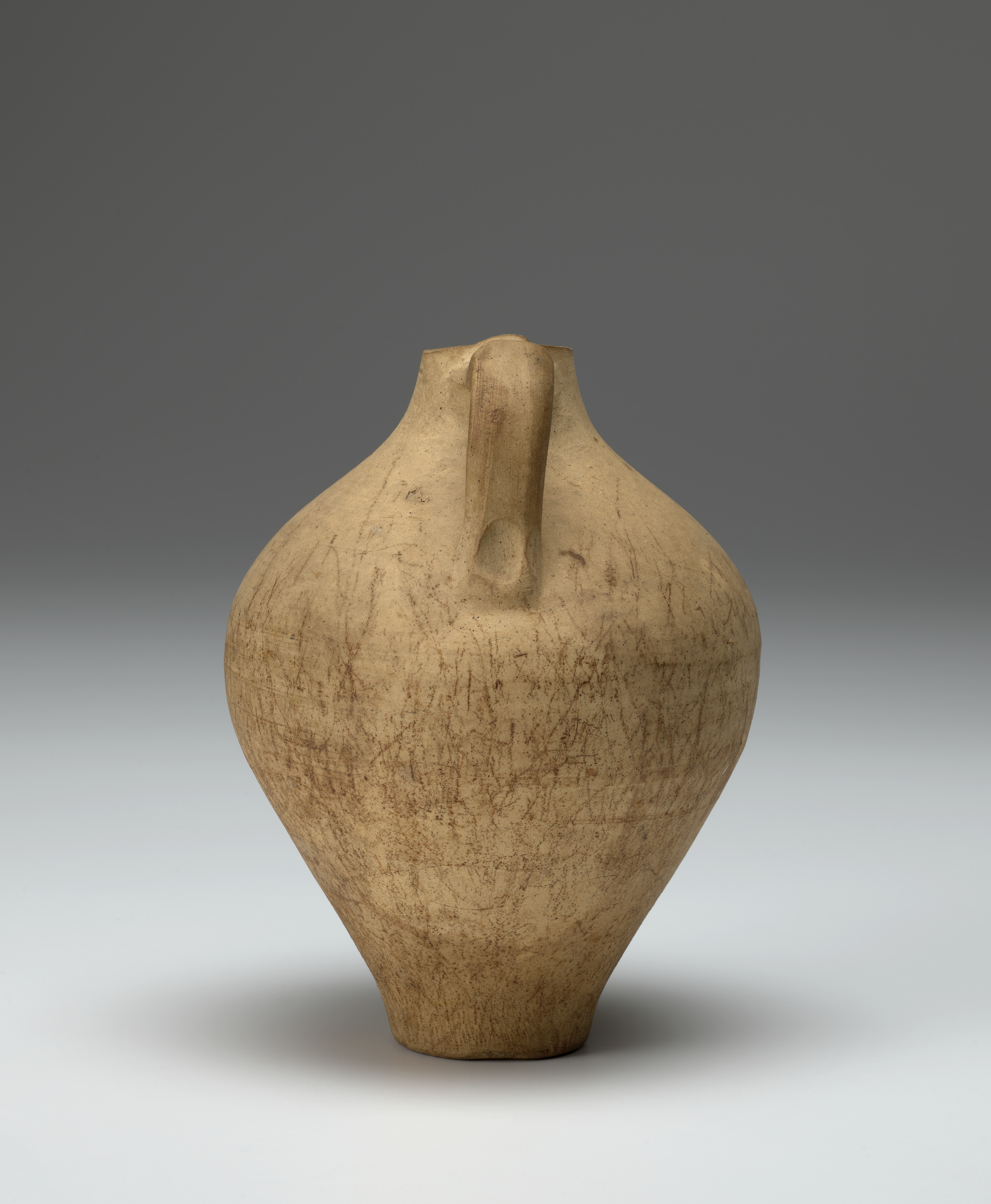 A yellow-beige ceramic jar with a handle and a spout.