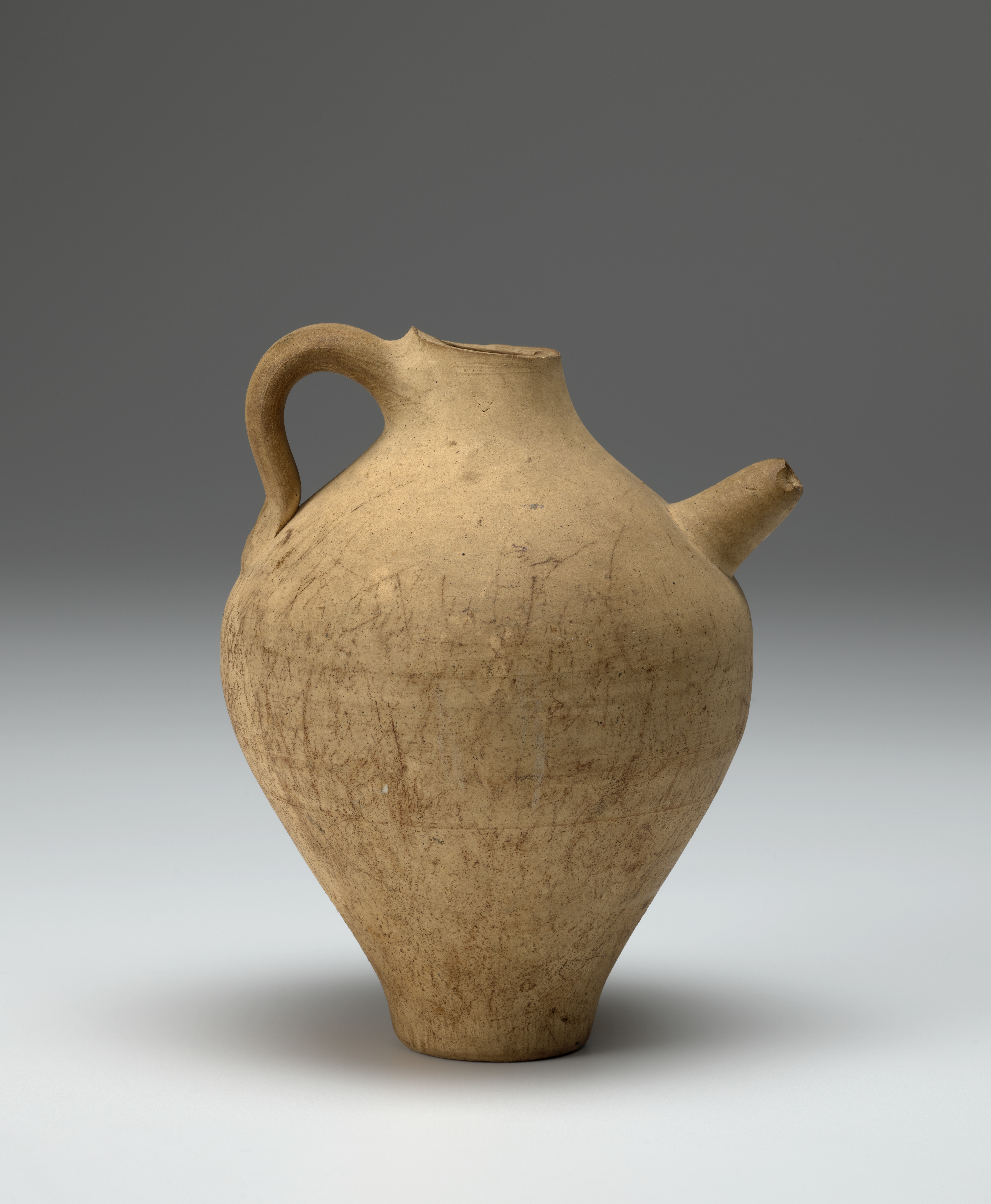 A yellow-beige ceramic jar with a handle and a spout.