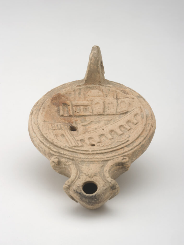 A reddish-beige, ceramic object with a rounded body, spout, and small handle. Its concave top surface is decorated with a cityscape design.