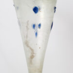 A cone-shaped glass lamp with a blue-green tint and dots of blue glass scattered across its surface.