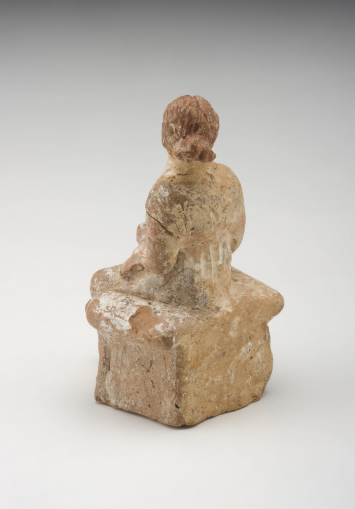 A clay sculpture of a seated woman dressed in a long, sleeveless gown.