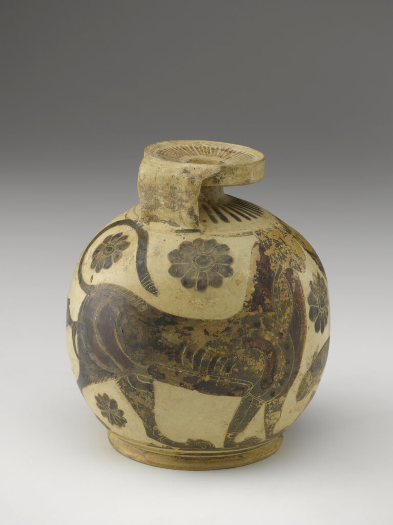 A beige-colored clay pot with a round base, a small neck, a handle, and flat mouth. It is decorated with black painted designs of flowers, a dolphin, and geometric shapes.