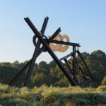 A large brown abstract sculpture in a grassy field