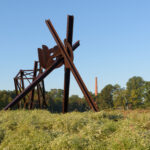 A large brown abstract sculpture in a grassy field