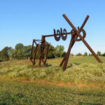 A large brown abstract sculpture in a grassy field