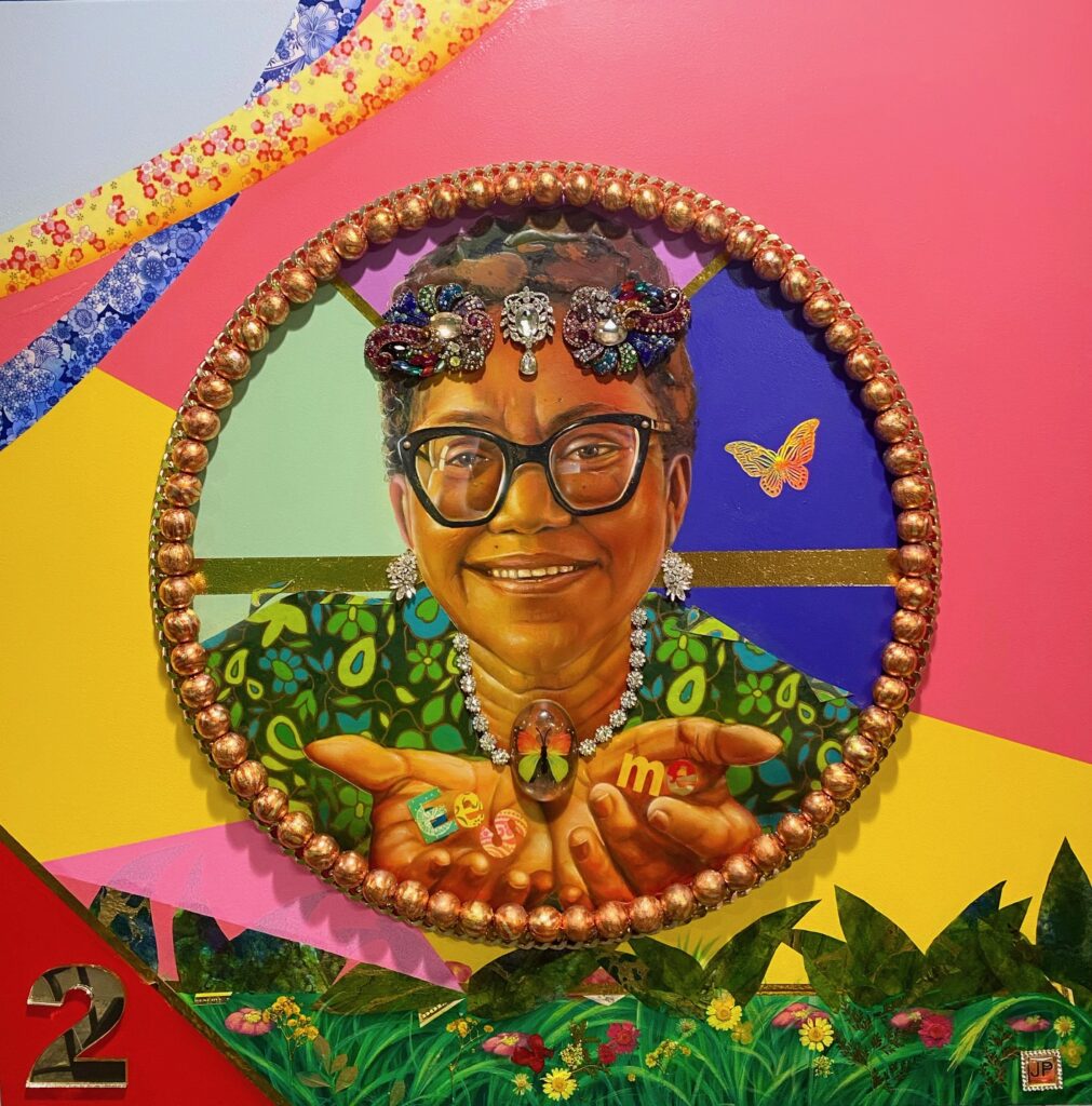 Three brightly colored portraits against an abstract backdrop. The portrait on the left depicts an older woman wearing glasses. The middle portrait depicts a mother and young son. The portrait on the right depicts a young girl. The paintings have a shiny surface and jeweled decoration. The backdrop is multicolored and features the profile of a woman’s head in blue. It also features images of four abstract tree branches, with birds sitting on them and birds in flight. The artist, Jermaine Powell, stands in front of his work wearing a green sweater.