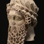 A picture of an ancient ceramic statue head with a large beard