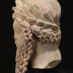 A picture of an ancient ceramic statue head with a large beard