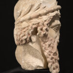 A picture of an ancient ceramic statue head with a large beard