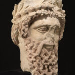 A picture of an ancient ceramic statue head with a large beard