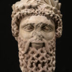 A picture of an ancient ceramic statue head with a large beard