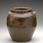 A brown ceramic jar with a date and name inscribed at the top