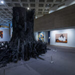 A large-scale abstract black sculpture that resembles a tree stump