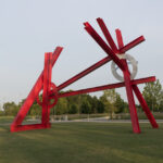 A large red abstract sculpture in an outdoor setting