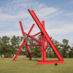 A large red abstract sculpture in an outdoor setting