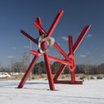 A large red abstract sculpture in a snowy outdoor setting