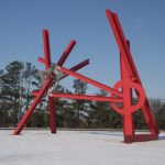 A large red abstract sculpture in a snowy outdoor setting