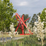 A large red abstract sculpture in an outdoor setting