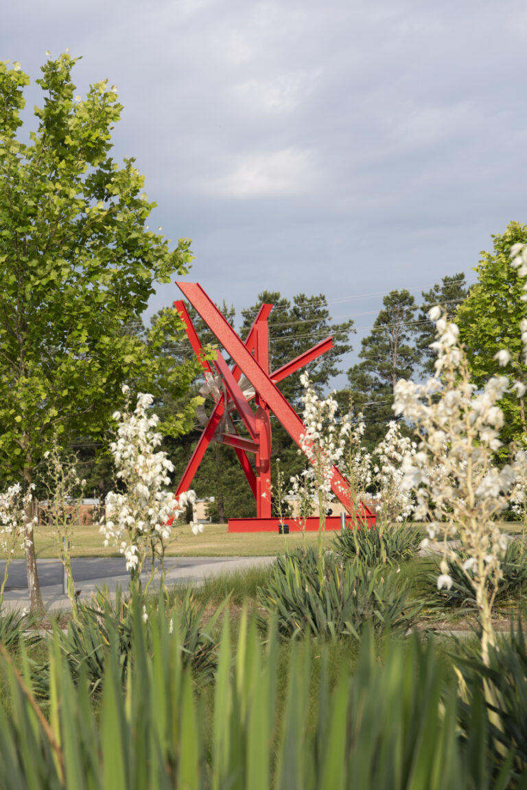 A large red abstract sculpture in an outdoor setting