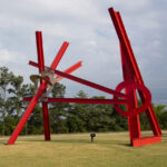 A large red abstract sculpture in an outdoor setting