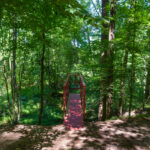 A dirt path leads to a red platform overlooking a wooded area