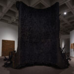 A large-scale abstract black sculpture that resembles a tree stump