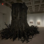 A large-scale abstract black sculpture that resembles a tree stump