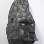 A gorilla head sculpture made from stitched black leather and paper