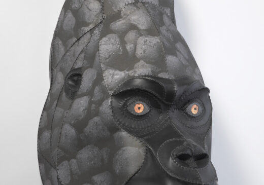 A gorilla head sculpture made from stitched black leather and paper