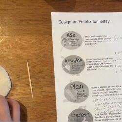 Worksheet and student's hands touching a clay disc