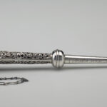 Silver Torah pointer featuring swirling designs, Hebrew text, and a tiny pointing hand