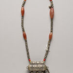 Silver and amber beaded necklace with tube-shaped pendant featuring dangling chains and bells
