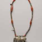 Silver and amber beaded necklace with tube-shaped pendant featuring dangling chains and bells