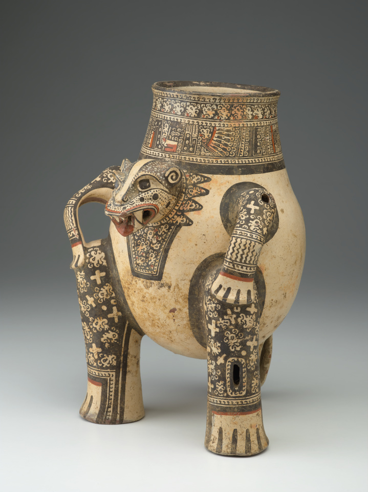 A painted terracotta vessel shaped like a crouching animal with patterned limbs and tail, open-mouth spout, and intricate black, cream, and red designs.
