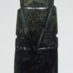 A dark-green, capsule-shaped jadeite pendant with an abstract face and line carvings.