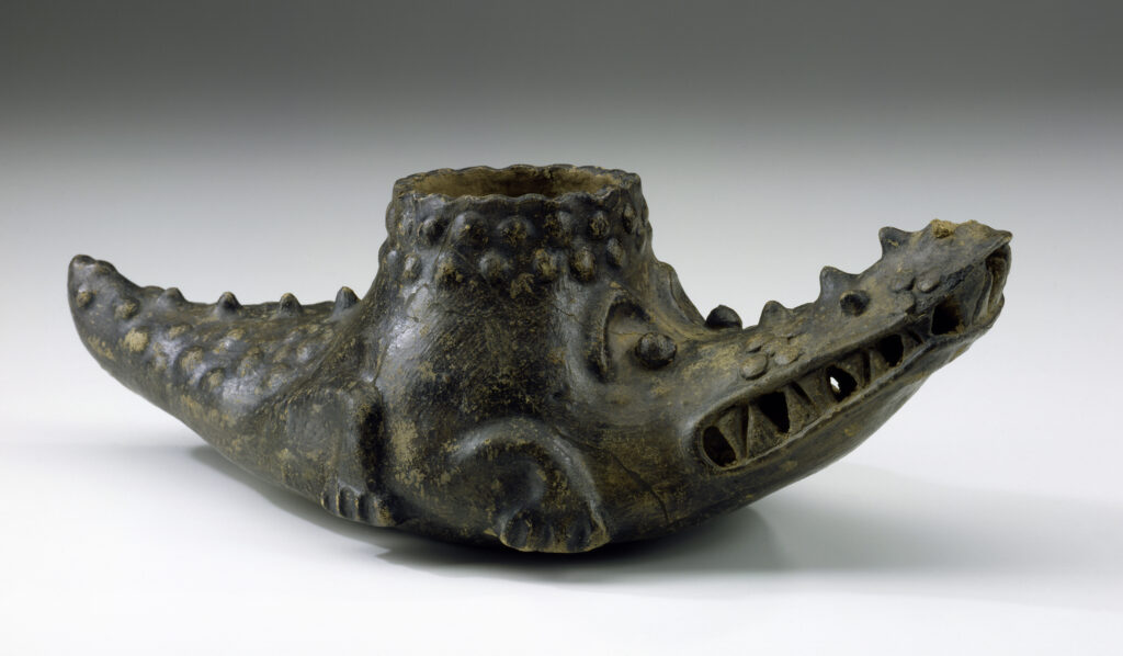 A brown crocodile-shaped ceramic vessel with a round opening on its back.