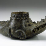 A brown crocodile-shaped ceramic vessel with a round opening on its back.