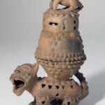 A ceramic incense burner with two separate pieces: a perforated animal-shaped base and a stacked, pierced lid topped by a small crouching creature.
