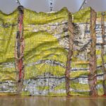 Large mixed media sculpture made of multicolored metal pieces connected together to resemble crumpled aluminum foil, displayed horizontally.